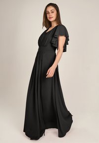 Schwarzes Maxikleid aus glattem Stoff, mit schwingenden Ärmeln, einer taillierten Taille und einem fließenden Rock mit Falten und einer klassischen Silhouette.