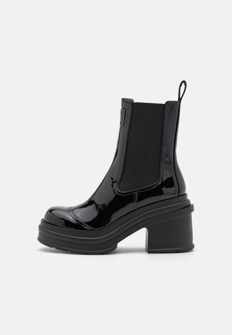 Botas negras de tobillo con un acabado brillante de charol, paneles laterales elásticos, una plataforma gruesa y un tacón cuadrado ancho para mayor estabilidad.