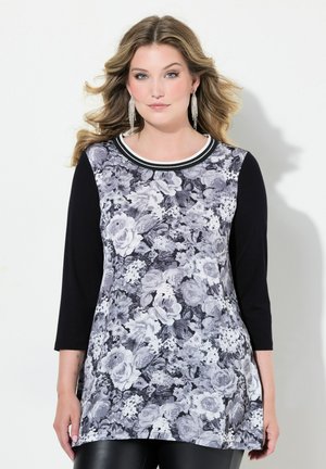 Blumenmuster Langarm-Tunika in Schwarz und Weiß, mit einem runden Ausschnitt und kontrastierender Borte sowie einem fließenden Design mit Blumenmustern.