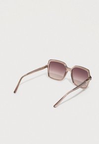 Gafas de sol con montura geométrica de tono rosa y lentes degradados. Presentan varillas delgadas de metal y detalles grabados en las bisagras.