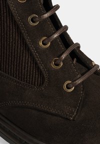 Bruine suède laars met een textuur van corduroy, bronzen oogjes en donkere veters, ontworpen voor duurzaamheid en comfort.