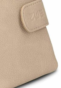 Esquina de cartera texturizada beige con cierre de solapa cosido, embellecida con un logo de marca parcialmente visible.