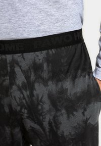 Czarne dresy z efektem tie-dye, wykonane z teksturowanej tkaniny, z elastycznym paskiem w talii, z delikatnym nadrukiem słów "PAWO HOME".