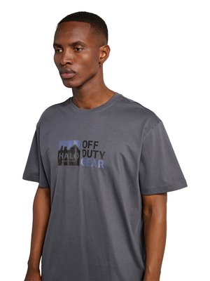 Mann trägt graues T-Shirt mit der Aufschrift „HALO OFF DUTY GEAR“ und einer Berggrafik, leicht nach links blickend auf weißem Hintergrund.