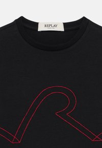 Svart bomull T-skjorte med en fremtredende rød brodert design. Rund hals og korte ermer. Merket leser "REPLAY SINCE 1981."