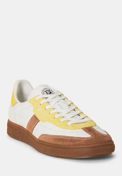 Λευκό, κίτρινο και καφέ χαμηλό παπούτσι τύπου sneaker με λευκά κορδόνια, σουέντ λεπτομέρειες, καφέ ελαστική σόλα και λογότυπο Polo Ralph Lauren στη γλώσσα και στην πλευρά.