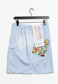 Svetle modrá cargo sukně se bočním kapsou a květinovým motivem. Visačka obsahuje pokyny k údržbě a detaily značky.