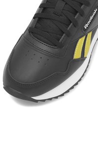 Čierne kožené tenisky so žltými akcentmi, so štruktúrovaným sieťovaným jazykom a okrúhlou špičkou. Obsahujú čierne šnúrky a bielu medzipodrážku.