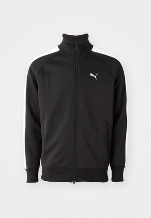 Must musta ülesse tõmmatav jakk, mis on valmistatud siledast kangast, valgete külgtriipudega ja kõrge kraega, väikese valge Puma logo jao peal.