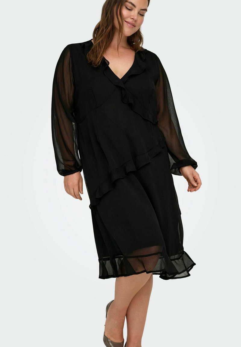 Czarna sukienka z falbanami, długimi przezroczystymi rękawami, dekoltem w kształcie litery V i warstwową spódnicą. Gładka tekstura, długość do kolan.