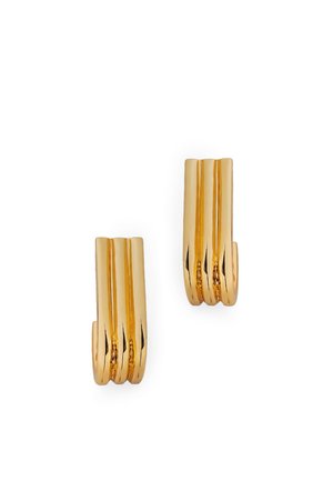 Paire de boucles d'oreilles clips en métal ton or brillant avec un design ondulé et côtelé sur fond blanc.