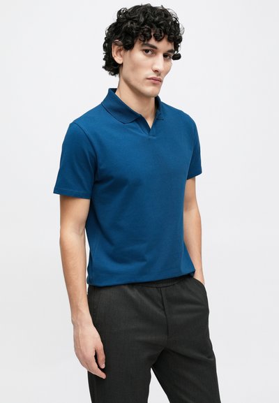 Īsrokas polo krekls tumši zilā kokvilnā ar klasisku apkakli. Piemērots ar tumšām biksēm, kas ir piegrieztas un ar smalku tekstūru.