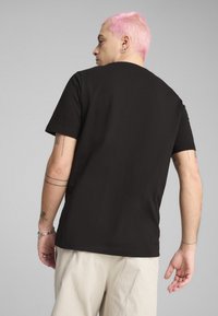 Sort bomulds T-shirt med korte ærmer, rund hals, lige snit og synlige sømme. Bæres med lyse bukser. Simpel design.