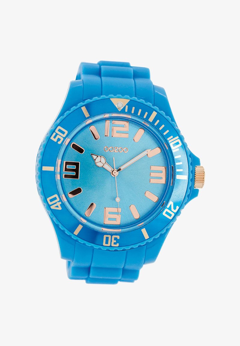 Montre en silicone bleue avec un cadran rond, un cadran bleu clair, des index en or rose et une couronne dorée, présentant une lunette texturée et des incréments numérotés.