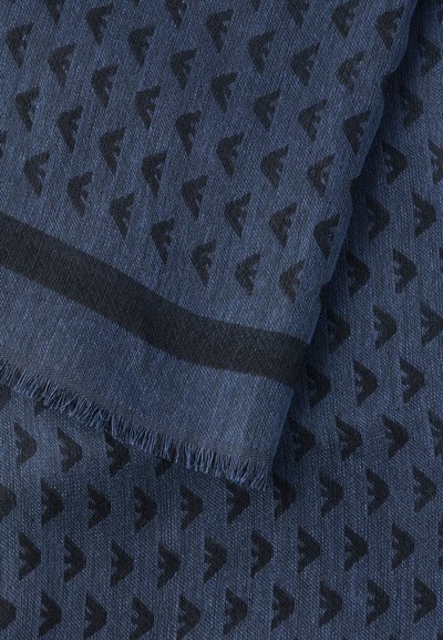 Modrá tkanina s opakujúcim sa tmavým abstraktným logom a čiernym okrajom s strapcami.