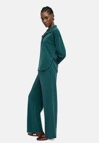 Zestaw z dzianiny w kolorze zielononiebieskim, składający się z długiego rękawa z okrągłym dołem i szerokich spodni. Miękka tekstura, luźny krój, z minimalnymi detalami sprzętowymi.