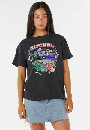 T-shirt en coton noir avec un impression graphique colorée représentant une scène de plage, des fleurs, et le texte "RIPCURL". Associé à une jupe en denim bleu clair.