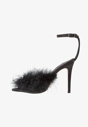 Des chaussures à talons hauts noires avec un bout pointu, dotées d'une sangle et d'un accent en plume noire duveteuse. Matériau en cuir lisse avec une finition brillante.