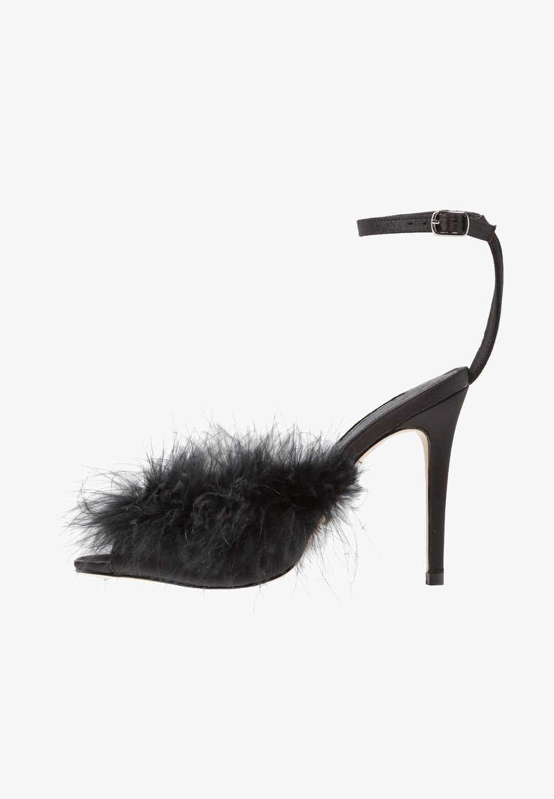 Des chaussures à talons hauts noires avec un bout pointu, dotées d'une sangle et d'un accent en plume noire duveteuse. Matériau en cuir lisse avec une finition brillante.