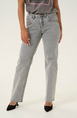Light gray high-waisted jeans with straight legs, prominent stitching, front pockets, and a button closure, paired with black pointed heels.