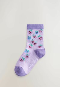 Lillasest varbast, kandast ja äärtest lilla värvi sokk, kaunistatud väikeste naeratavate puuviljanägudega sinises, roosas ja lillakas, tasapinnal heledal taustal.