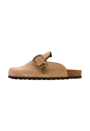 Sabot beige en cuir suédé sans lacets avec grande boucle en laiton, semelle intérieure en liège et semelle extérieure en caoutchouc noir texturé, vu de profil.