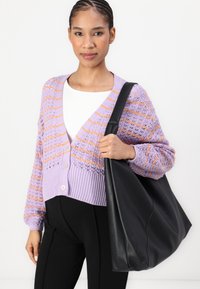Cardigan viola in cotone con strisce arancioni, chiusura a bottoni e orlo a coste; abbinato a una borsa a tracolla in pelle nera.