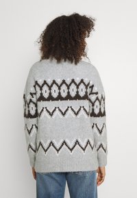 Pull en maille gris avec des motifs marron et blanc. Oeuvre d'une coupe décontractée et de manches longues, avec des poignets et un ourlet côtelés.
