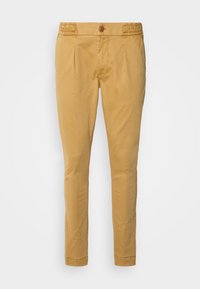 Pantalons en coton beige avec fermeture à bouton, texture lisse, jambes fuselées et plis devant. Conçus pour une silhouette ajustée.