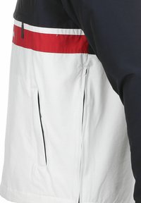 Herrejakke med marinebl�å overdel, rød og hvit horisontal stripe, glidelåslommer på sidene og glatt, lett stoff.