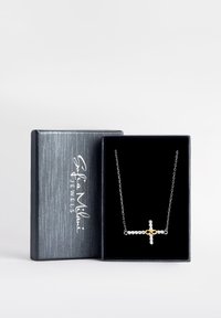Silver cross necklace with gold infinity accent, adorned with clear stones. Presented in a black velvet-lined gray box.