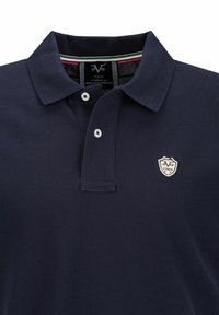 Marineblauw polo shirt met een gestructureerde kraag, drie witte knopen en een klein schildlogo met beige en zwarte accenten.