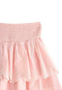 Gonna di cotone rosa con top arricciato, caratterizzata da strati arricciati e dettagli ricamati bianchi lungo l'orlo, texture morbida e design leggero.