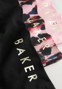 Tři páry šortek v černé a růžové. Jedny mají černý základ, zatímco druhé mají barevný skvrnitý vzor se zlatým nápisem "BAKER."