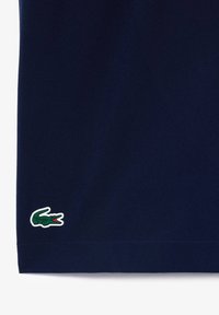 Navy blue short-sleeved polo shirt with a textured fabric. Features a green, embroidered crocodile logo at the hem. Classic fit.