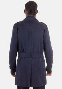 Trench coat blu navy con vita cintata, sottoguerra sulle spalle e un tessuto leggermente texturizzato, caratterizzato da un design di lunghezza media e una finitura liscia.