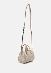 Borsa a mano beige con motivo a logo, forma arrotondata, manici doppi e tracolla lunga regolabile. Presenta componenti in tonalità oro e una finitura testurizzata.