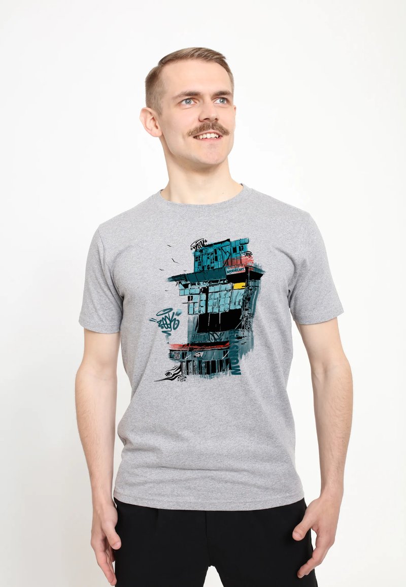 Camiseta de algodón gris con un diseño gráfico colorido de un edificio con acentos en azul, rojo y negro, que incluye patrones y texturas abstractas.