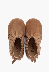 Zapatos infantiles de ante marrón con detalles de flecos, punta redonda y hebillas laterales. Interior con plantilla de marca. Textura suave.