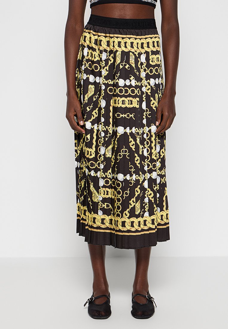 Jupe plissée noire avec un motif de chaîne dorée et blanche. Taille élastique, tissu fluide et coupe mi-longue pour faciliter les mouvements.