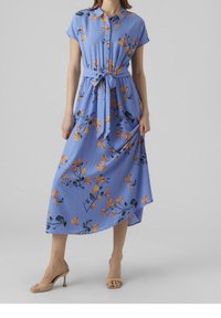 Sininen kukkakuosiset mekko, joka on valmistettu kevyestä kankaasta. Mekossa on nappikiinnitys edessä, lyhyet hihat ja vyötäröllä solmittava vyö.