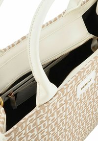 Borsa in tessuto beige e bianca con esterno decorato, doppi manici, chiusura con zip e interno nero dotato di tasche organizzative.