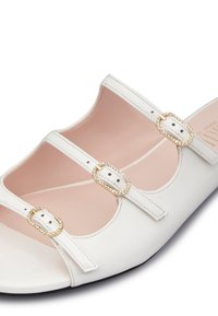 Sandal aperta bianca con punta scoperta, realizzata in morbida pelle e caratterizzata da tre cinghie decorative, ognuna con fibbie dorate e accenti di strass.