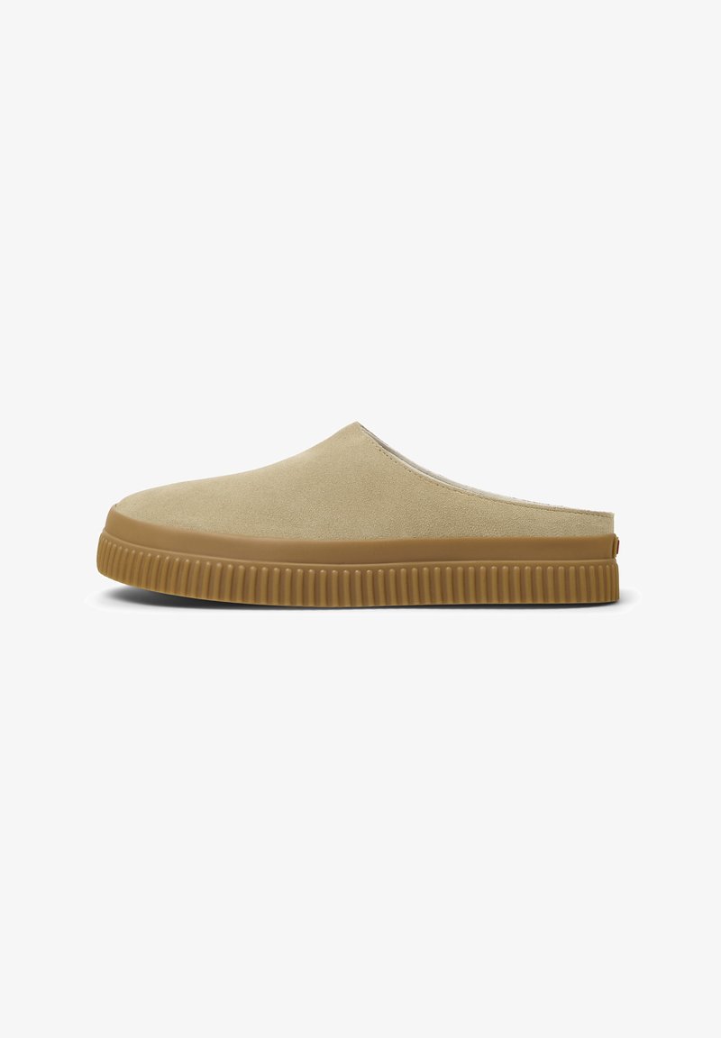Ανοιχτό μπεζ slip-on παπούτσια με λεία, σουέτ υφή και παχιές, ριγμένες καφέ καουτσούκ σόλες. Απλός σχεδιασμός, χωρίς ορατό υλικό.