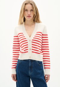 Červeno-bílý pruhovaný cardigan s hlubokým V výstřihem, předními knoflíky a ribovanými manžetami. Vyrobeno z měkkého materiálu, skvěle se hodí k modrým džínům.
