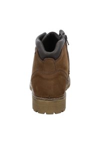 Bottine en daim marron avec un col en cuir, fermeture éclair arrière, semelle en caoutchouc texturée et détails de couture subtils.