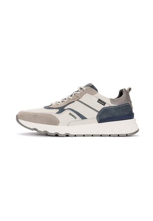 Zapatilla casual con paneles beige, azul marino y gris, suela blanca, cordones delanteros y etiqueta con marca cerca del tobillo.