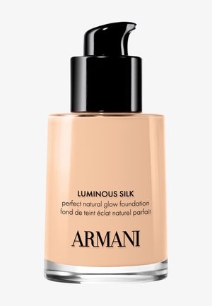 Fond de teint Luminous Silk dans une bouteille en verre transparent avec une pompe noire. Liquide beige pâle et lisse, avec un marquage minimaliste sur l'étiquette.