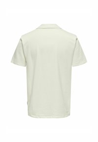 Kortärmad polo shirt i ljus kräm, med en texturerad våffeldesign, mjukt tyg och klassisk krage. Bakvy med rak fåll.