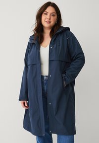 Navy waterdichte parka met een capuchon, front rits, drukknoopsluiting, twee grote zakken en verstelbare koordjes in de taille en aan de onderkant.